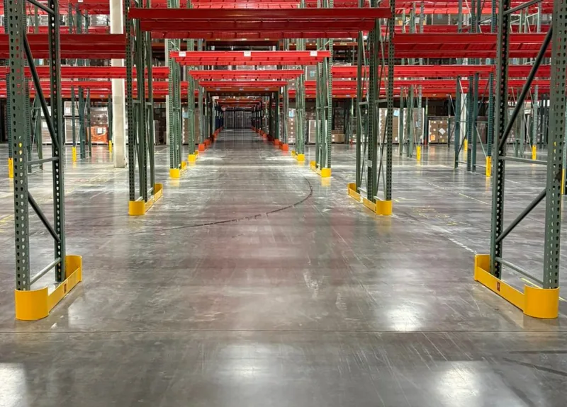 End-of-aisle rack guards at the base of every frame down a pallet rack aisle
